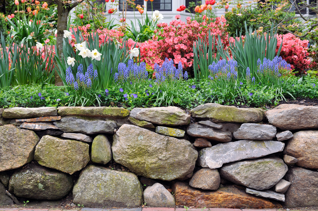 a rock garden wall with a colorful garden bed