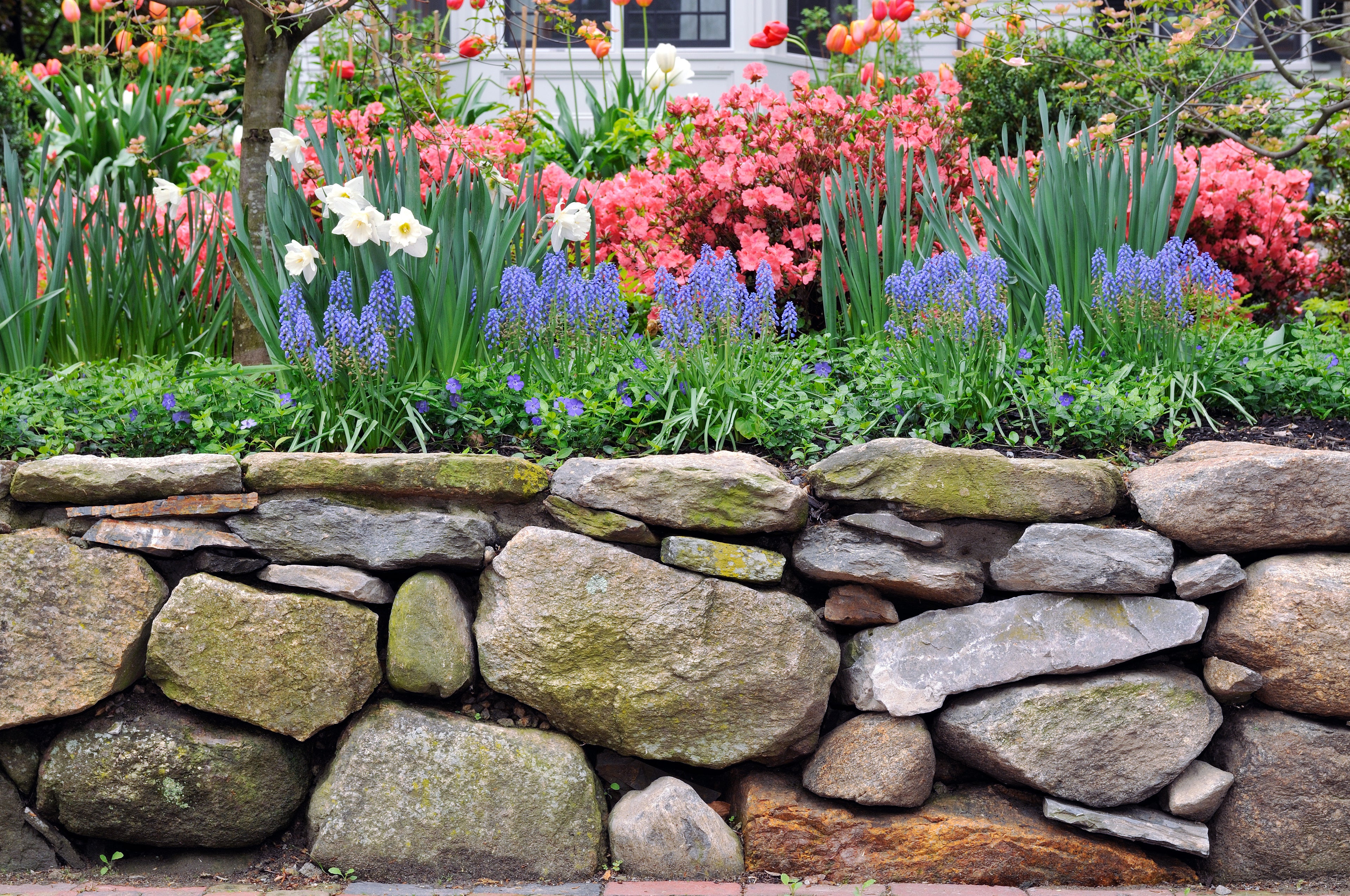 a rock garden wall with a colorful garden bed
