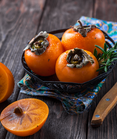Meader Common Persimmon fruit on a table, round orange skinned and orange fleshed fruit