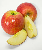 Pink Lady Apples on white, two round mostly red apples with light green blush and small white speckles along with a couple slices