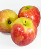Pink Lady Apples on white, three round mostly red apples with light green blush and small white speckles