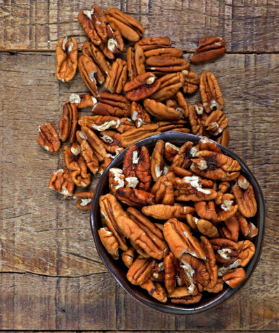 USDA Organic Orchard Select Pecan nuts in a dish, deshelled brown pecans in a dark brown bowl and on a wooden table