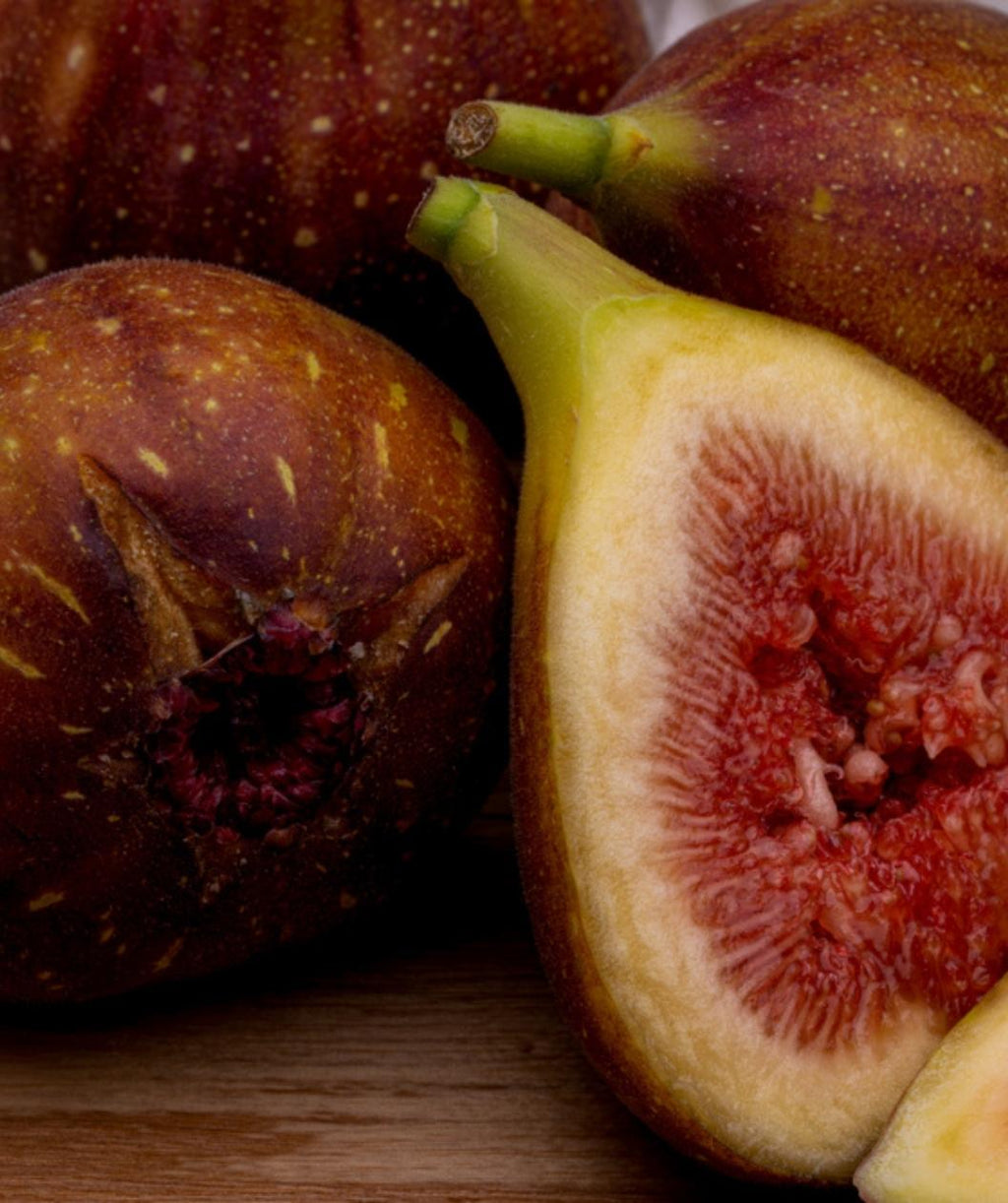 Close up of Brown Turkey Figs, several figs on a table with 1 cut in half showing the redish colored inside